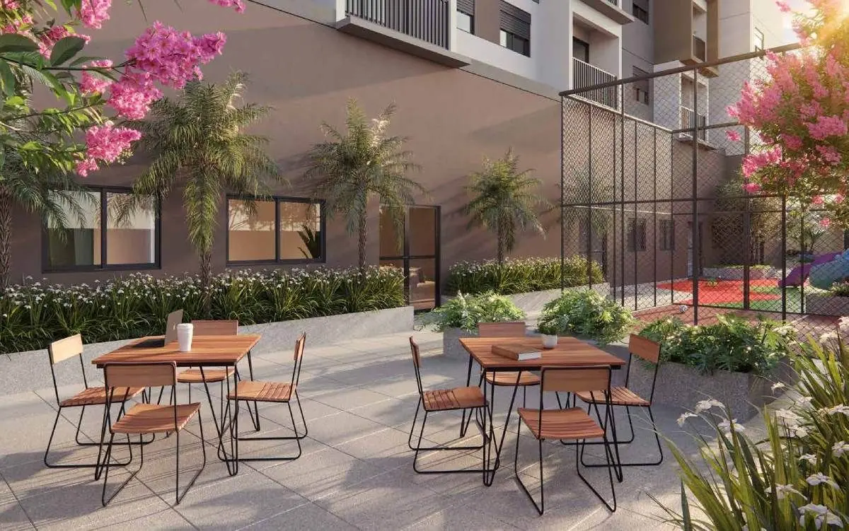 O apoio do coworking ao ar livre: mesas e cadeiras num pátio com plantas floridas.