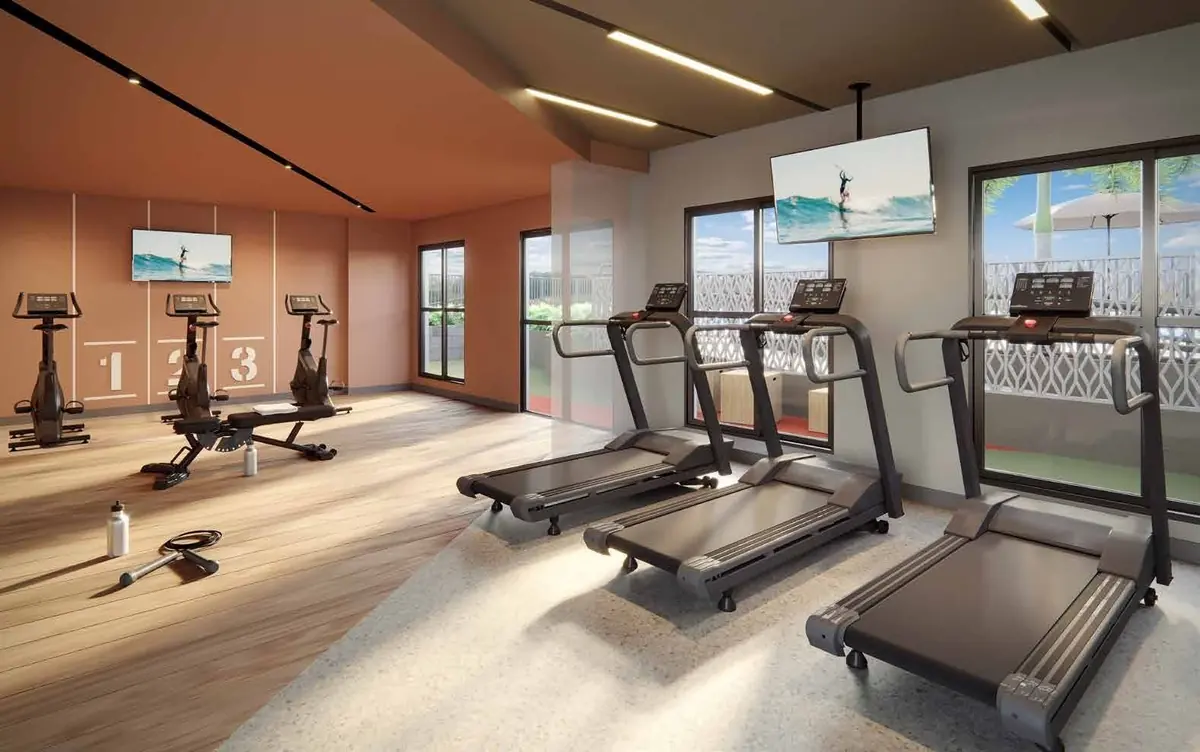 O fitness com esteiras diante da janela, bicicletas e um banco de exercícios.