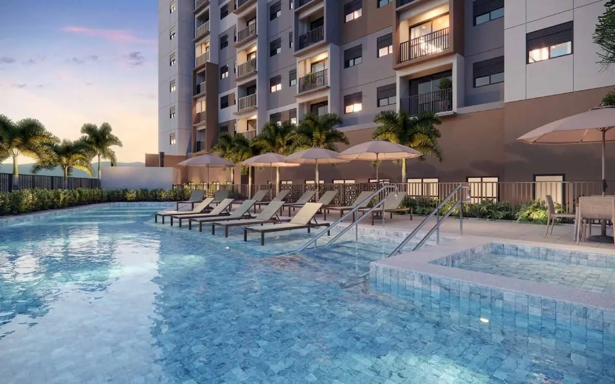 A piscina adulto e a infantil ao entardecer, com espreguiçadeiras, guarda-sóis e a torre ao fundo.