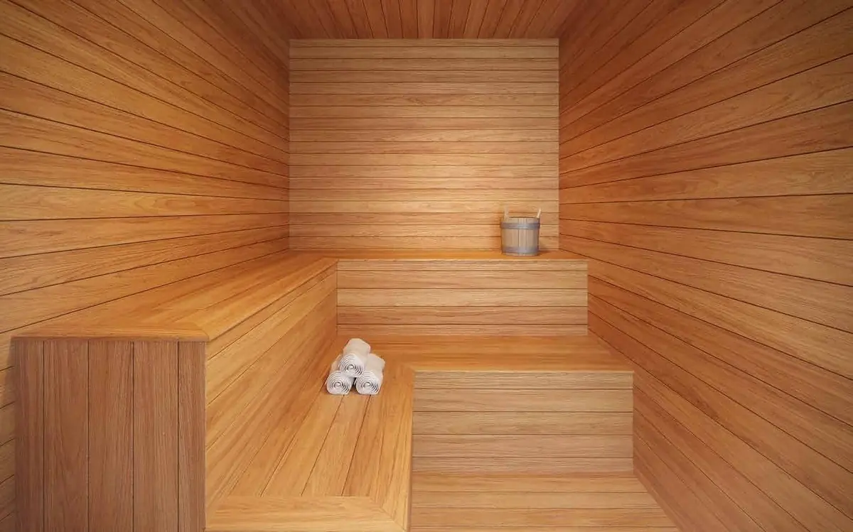 A sauna revestida de madeira, com bancos em degraus e toalhas enroladas.