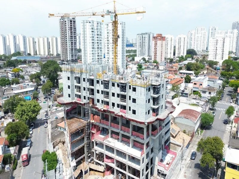 A torre em obra vista do alto, com a grua no topo e os prédios de Osasco ao fundo.