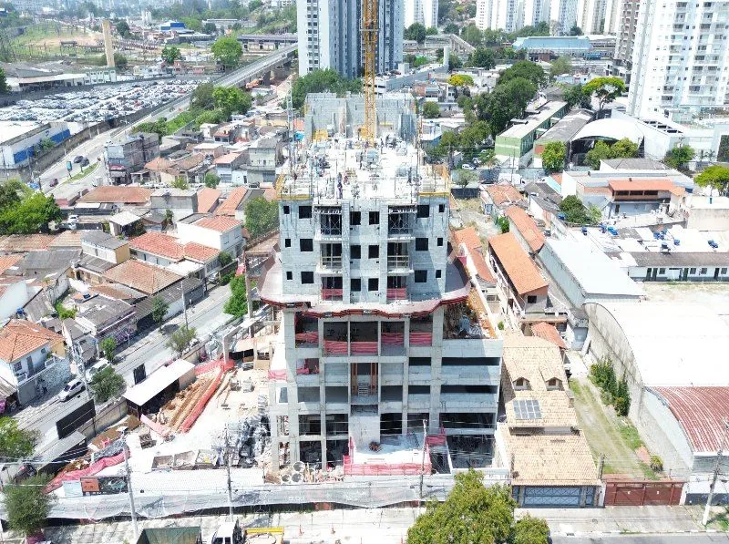A torre em obra de frente, com as telas de proteção e as casas de Presidente Altino em volta.