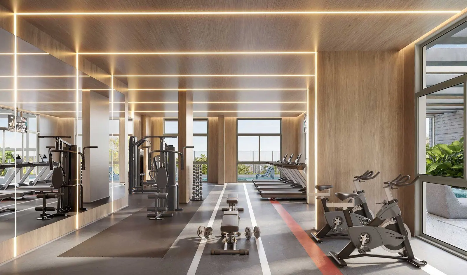 O fitness com as bicicletas, os aparelhos de musculação e a faixa vermelha no piso, sob o forro de madeira.
