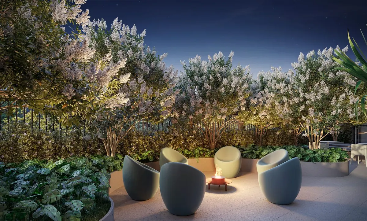 A praça do fogo à noite, com poltronas em volta da fogueira e o jardim florido.