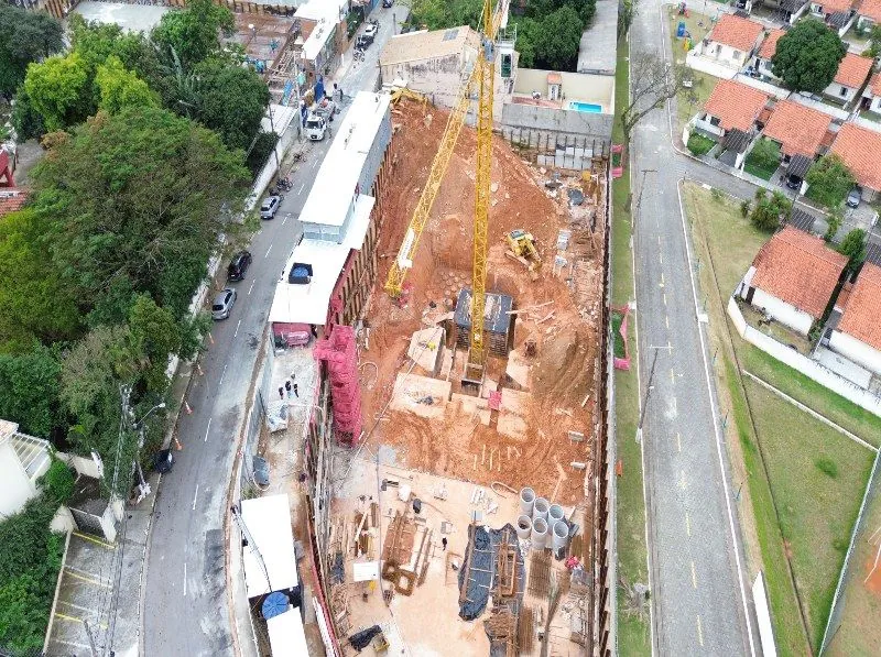 A obra vista de cima, entre duas ruas: a terra da fundação, a grua e os contêineres do canteiro.