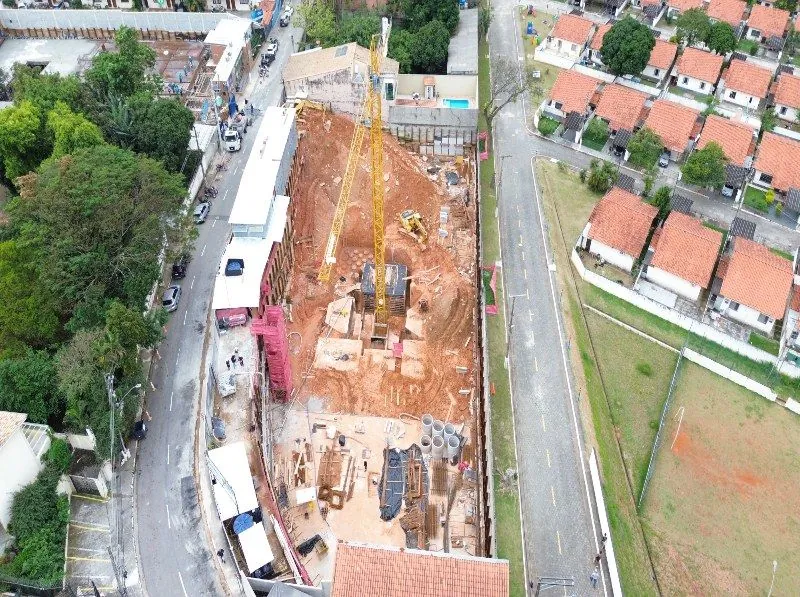 A fundação em andamento vista de cima, com a grua e as máquinas no canteiro.