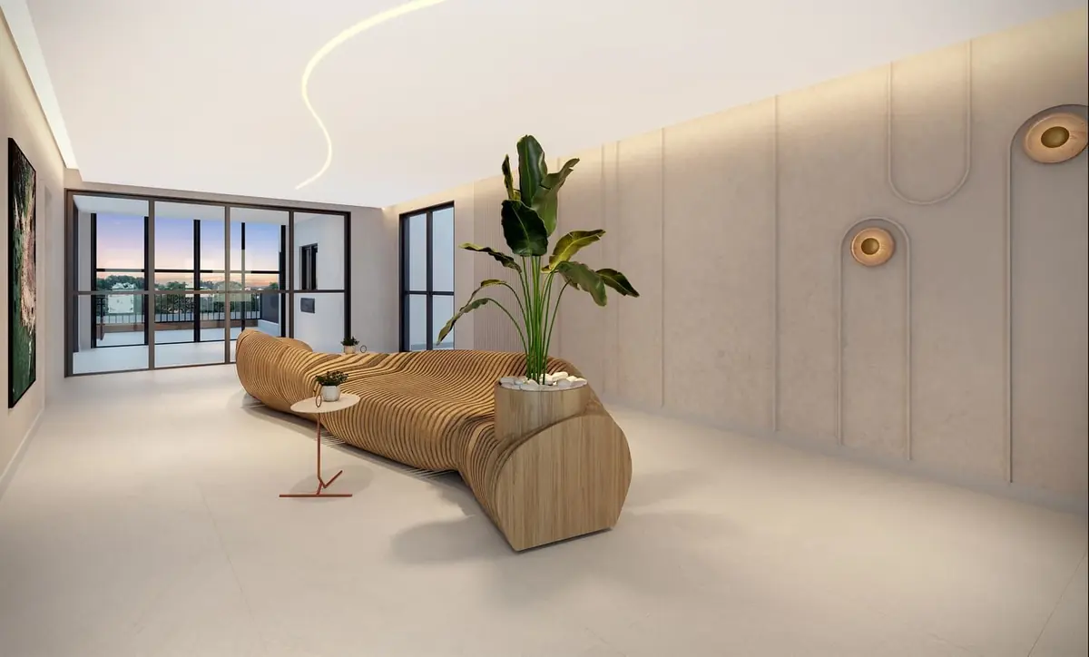 O lobby com um banco de madeira ondulado, uma planta alta e a parede clara com arandelas.