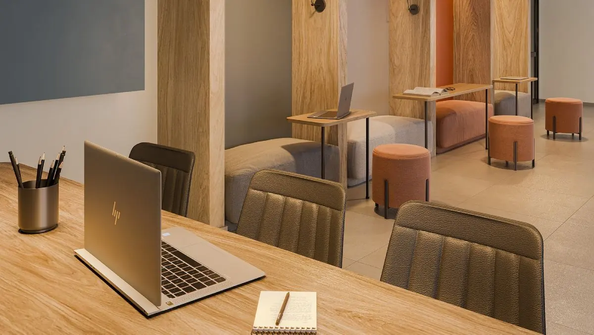 O coworking com mesas de trabalho, cadeiras estofadas e um notebook aberto.