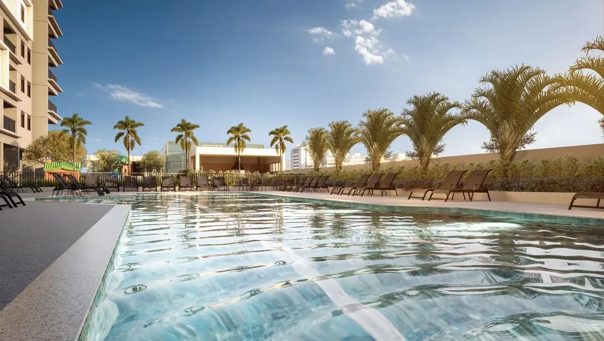 A piscina adulto ao entardecer, com palmeiras e as torres atrás.