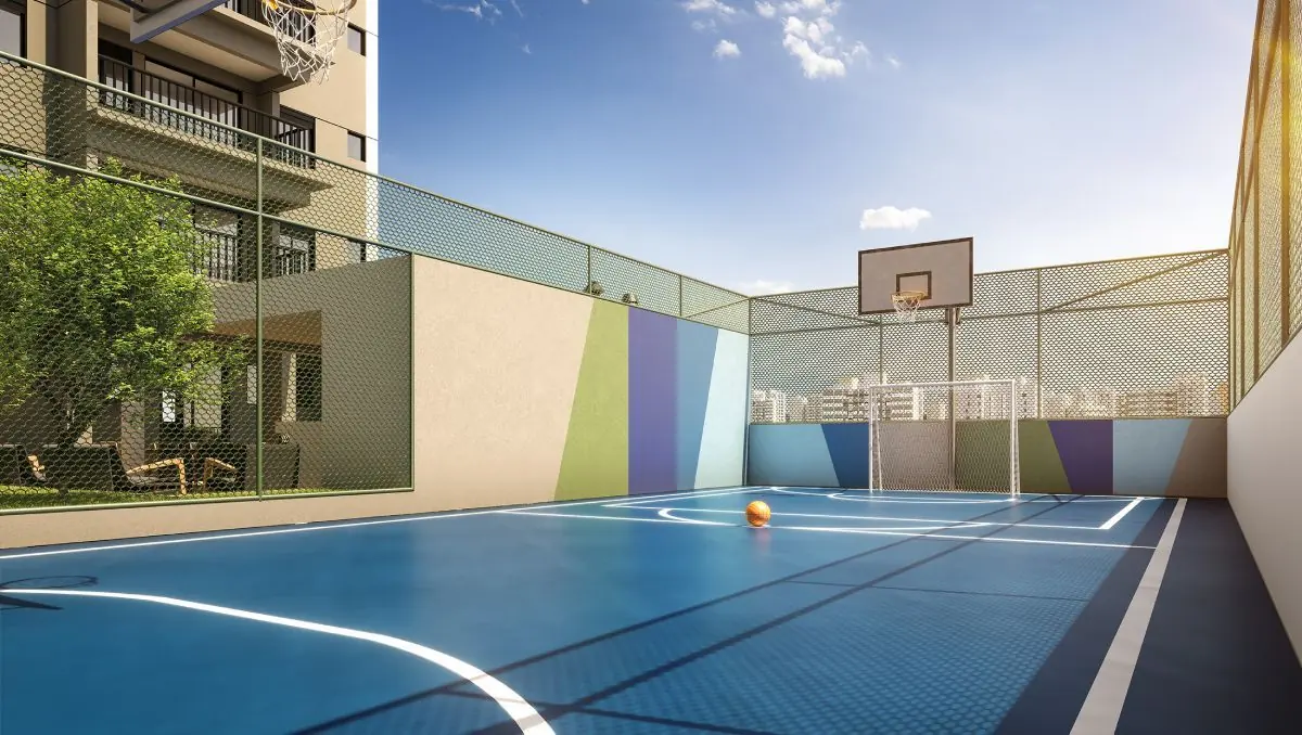 A quadra recreativa azul com tabela de basquete, cercada por alambrado.