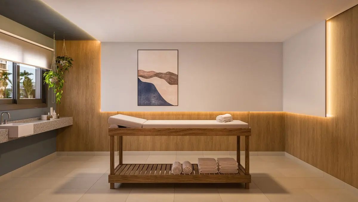 A sala de massagem com a maca de madeira e luz baixa.