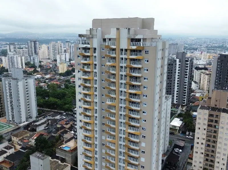 A torre do Altto Bela Vista vista do alto, entre os prédios e as casas do bairro, em dia nublado.
