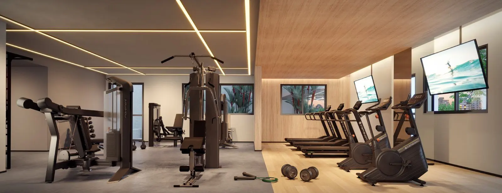 O fitness com esteiras e bicicletas diante das janelas e os aparelhos de musculação.