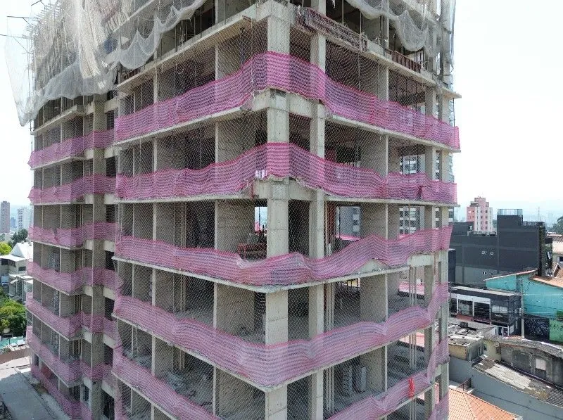 A fachada em obra de perto: as lajes, os pilares e as telas cor-de-rosa.